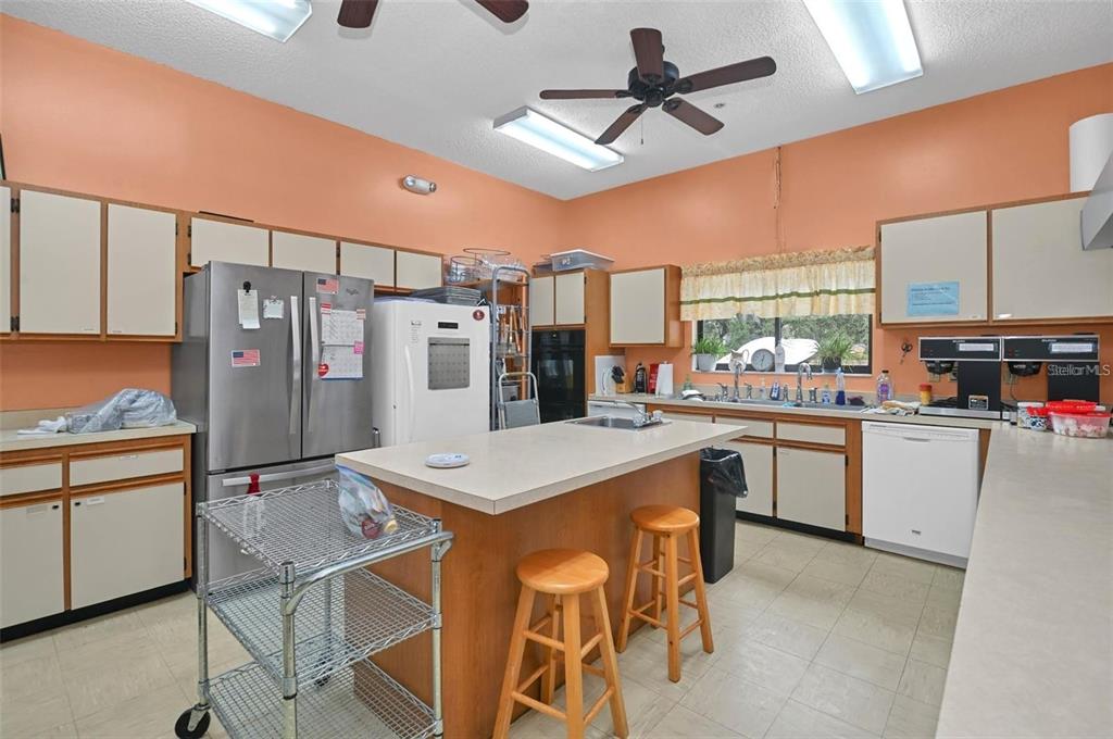 8449 Southwest 106th Place Ocala, FL 34481 - Photo 27 of 37 a kitchen with stainless steel appliances kitchen island granite countertop a refrigerator a stove top oven a sink dishwasher and white cabinets with wooden floor