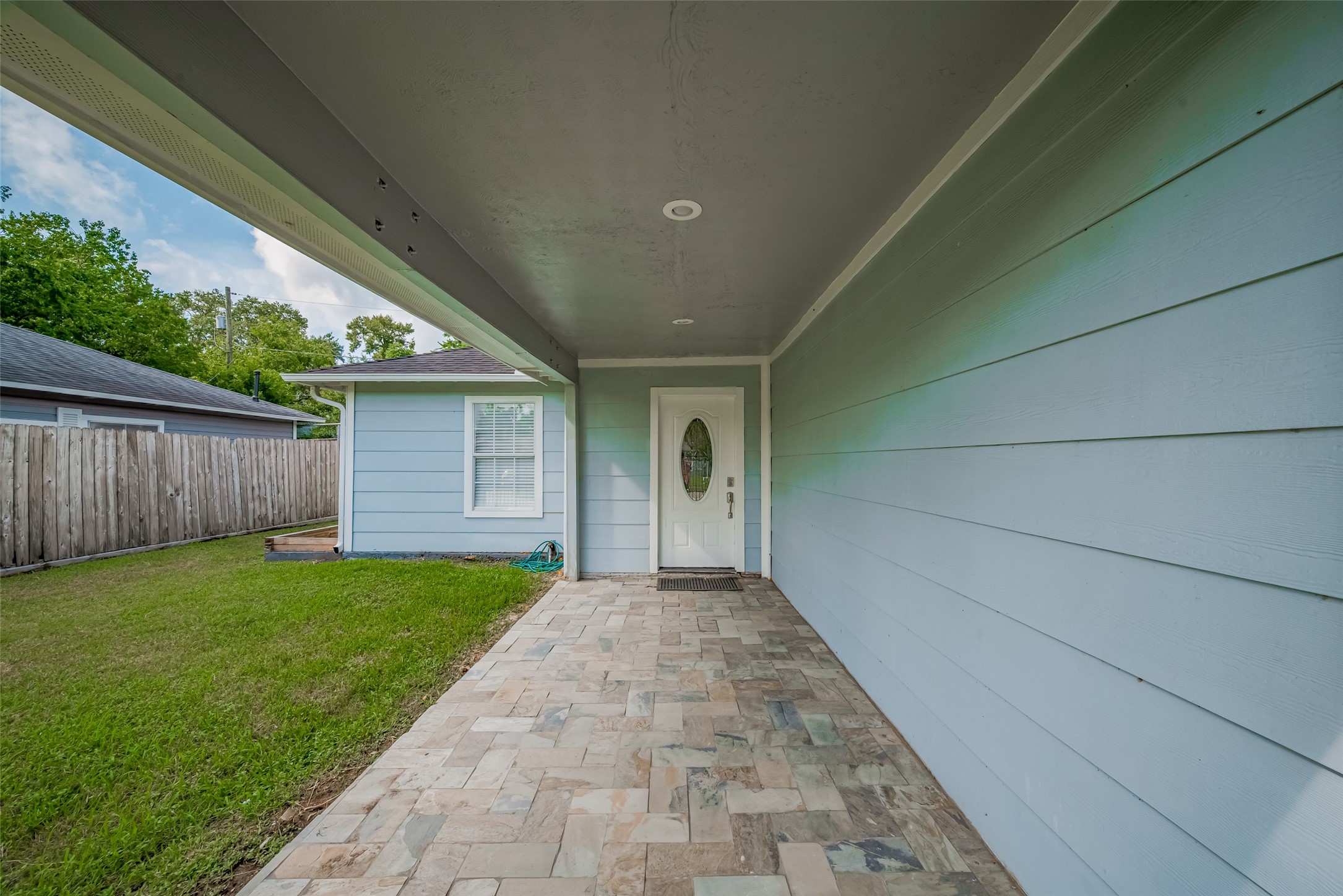3930 Daphne Street Houston, TX 77021 - Photo 7 of 44 Stroll beneath a covered walkway along a lush lawn, where the quiet simplicity of the landscaping sets a calm, intentional tone before you even open the door.