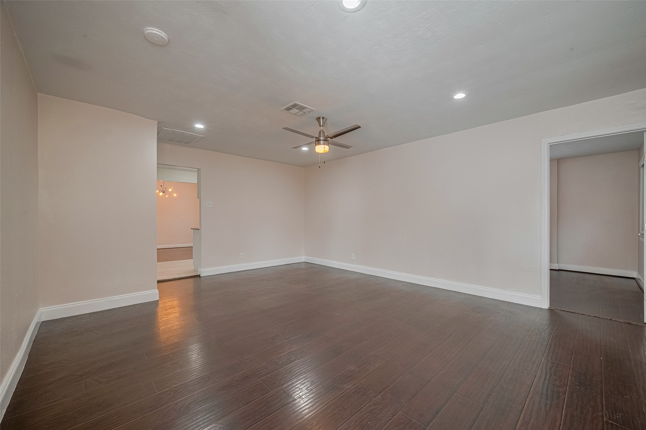 3930 Daphne Street Houston, TX 77021 - Photo 8 of 44 Inside, the living room opens up with striking dark flooring, recessed lighting, and a ceiling fan above—while an oversized window near the entry fills the space with natural light.