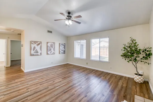 a view of an empty room with wooden floor and a chandelier