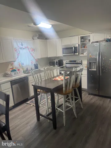 a dining area with stainless steel appliances kitchen island granite countertop a dining table chairs and a refrigerator