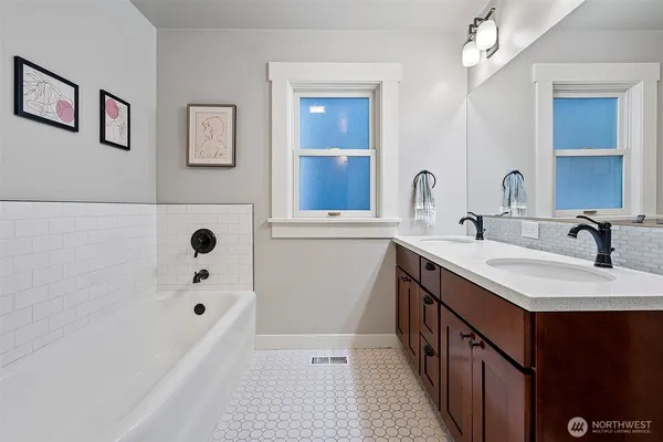 a bathroom with a tub a sink and mirror