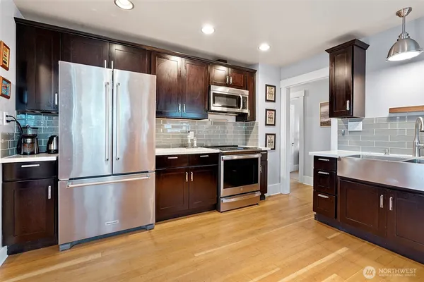 a kitchen with stainless steel appliances granite countertop a refrigerator a stove and a sink