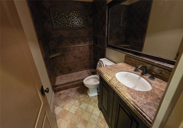 a bathroom with a granite countertop sink toilet and shower