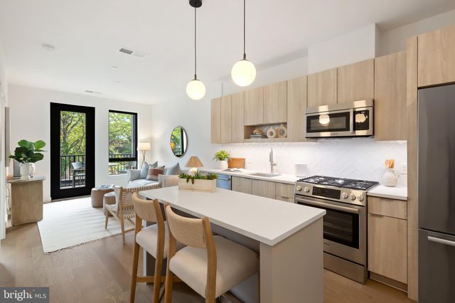 a kitchen with a stove a microwave a dining table and chairs with wooden floor