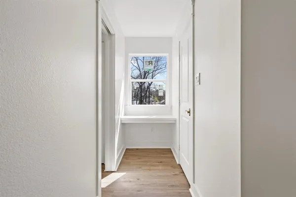 a view of a hallway with wooden floor and a window