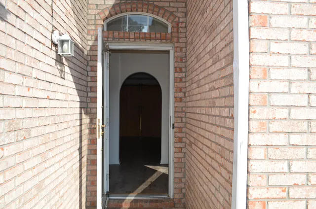 a view of an empty room with wooden floor and a fireplace
