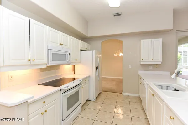 a large white kitchen with a sink a stove and a refrigerator