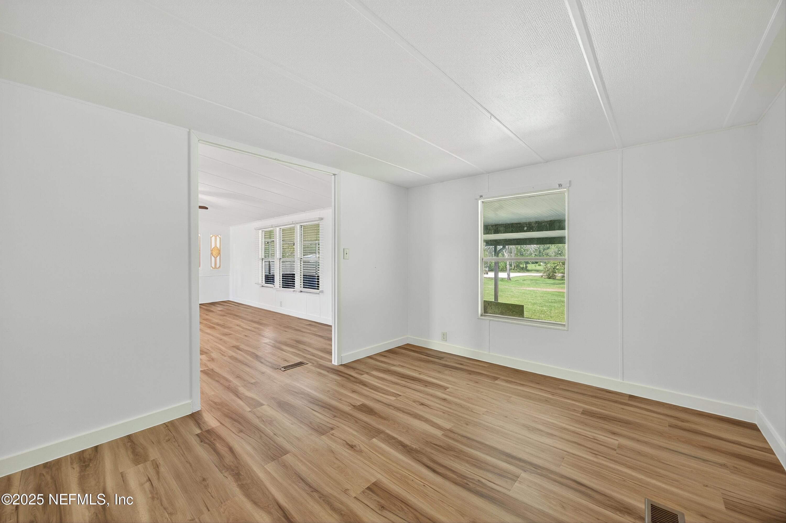 349 Stokes Landing Road St. Augustine, FL 32095 - Photo 14 of 45 a view of an empty room with wooden floor and a window