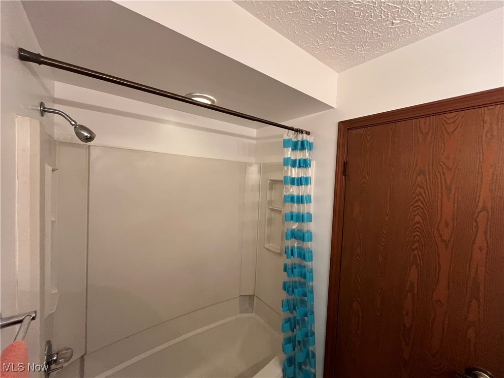 1455 Welch Road Painesville, OH 44077 - Photo 33 of 42 Bathroom with shower / bathtub combination with curtain and a textured ceiling