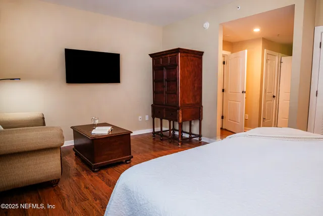 a bedroom with a bed a couch and a flat screen tv