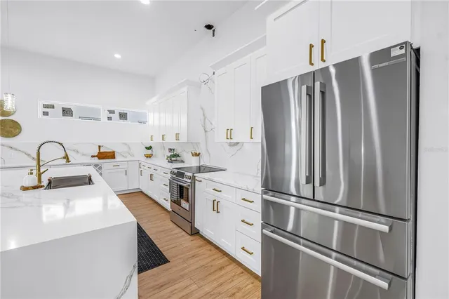 a kitchen with stainless steel appliances a refrigerator sink and white cabinets