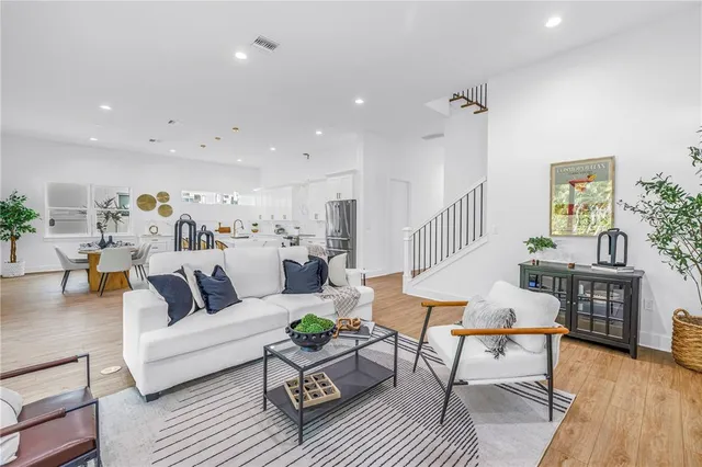 a living room with furniture kitchen view and a wooden floor