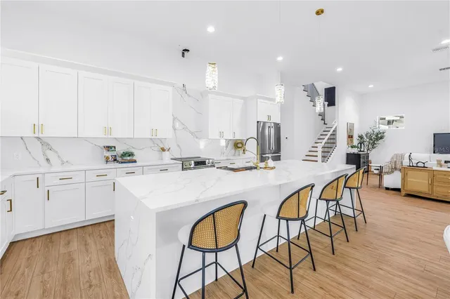 a kitchen with stainless steel appliances kitchen island granite countertop a table chairs sink and cabinets