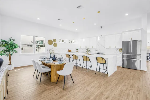 a kitchen with stainless steel appliances granite countertop a dining table chairs stove refrigerator and cabinets