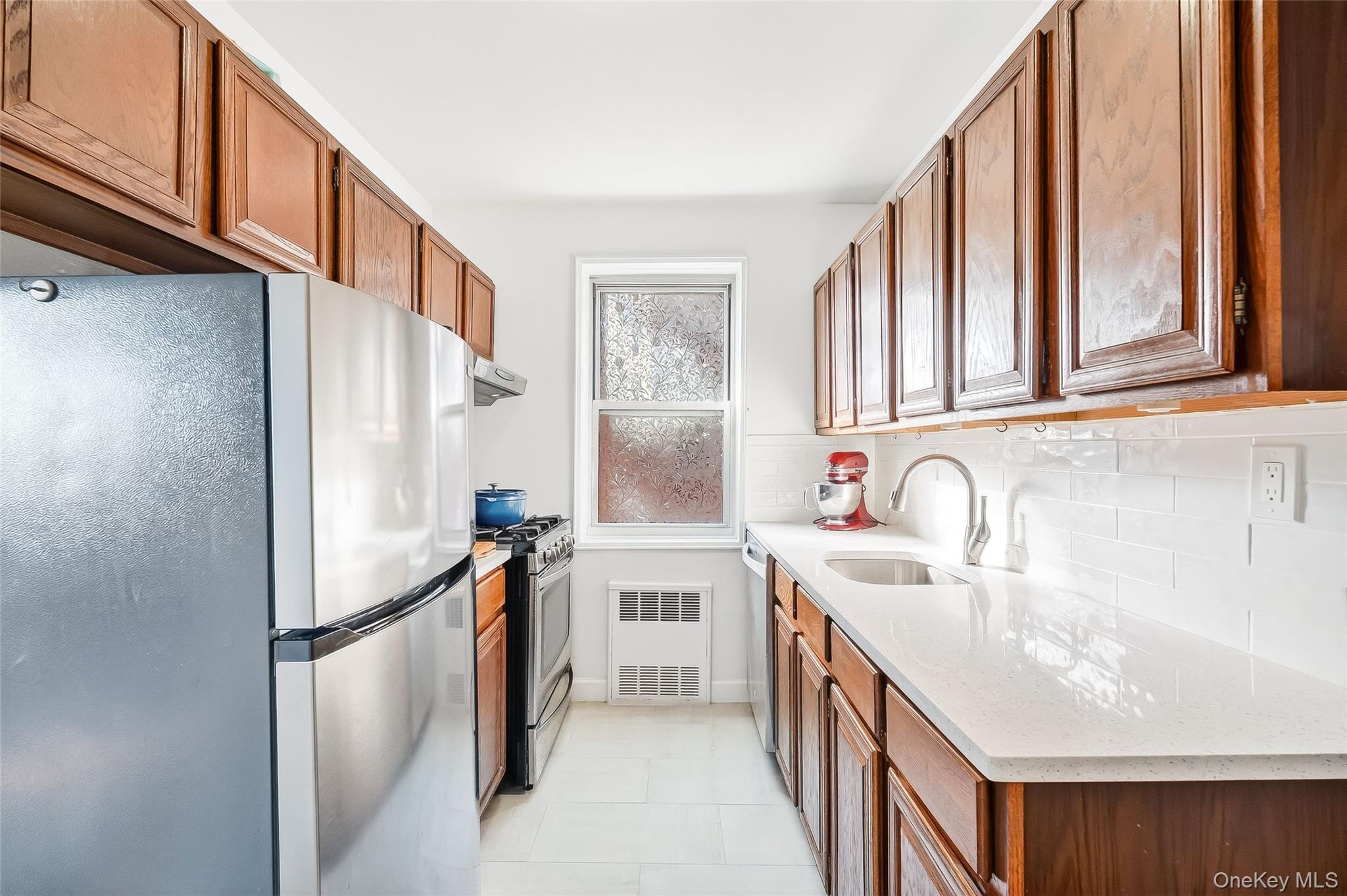 609 Palmer Road, Unit 5L Yonkers, NY 10701 - Photo 9 of 35 Kitchen with stainless steel appliances, tiled floor, quartz countertop and subway tile backsplash.