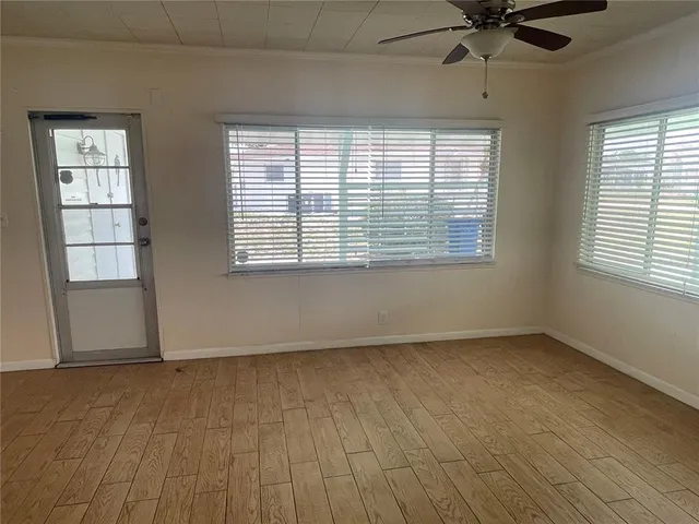 a view of an empty room with a window and wooden floor