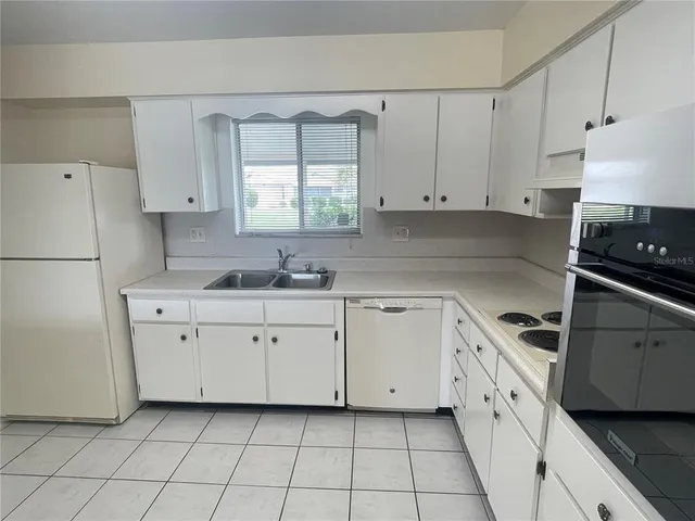 a kitchen with white cabinets appliances and a sink