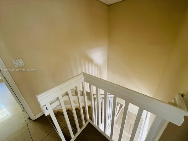 a view of staircase with railing and white walls