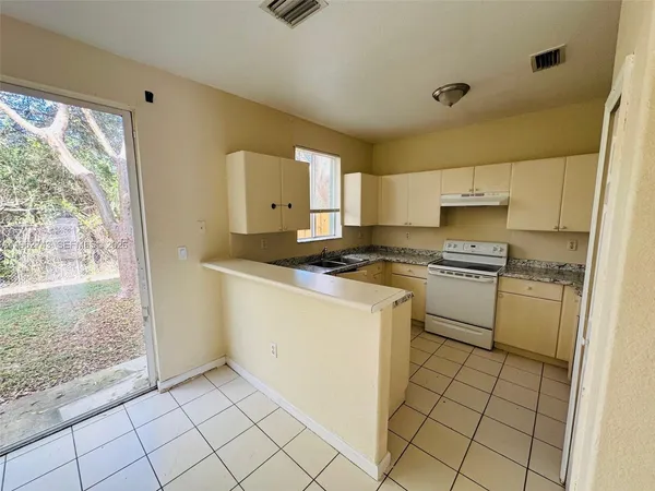a kitchen with white cabinets a sink a stove and a refrigerator
