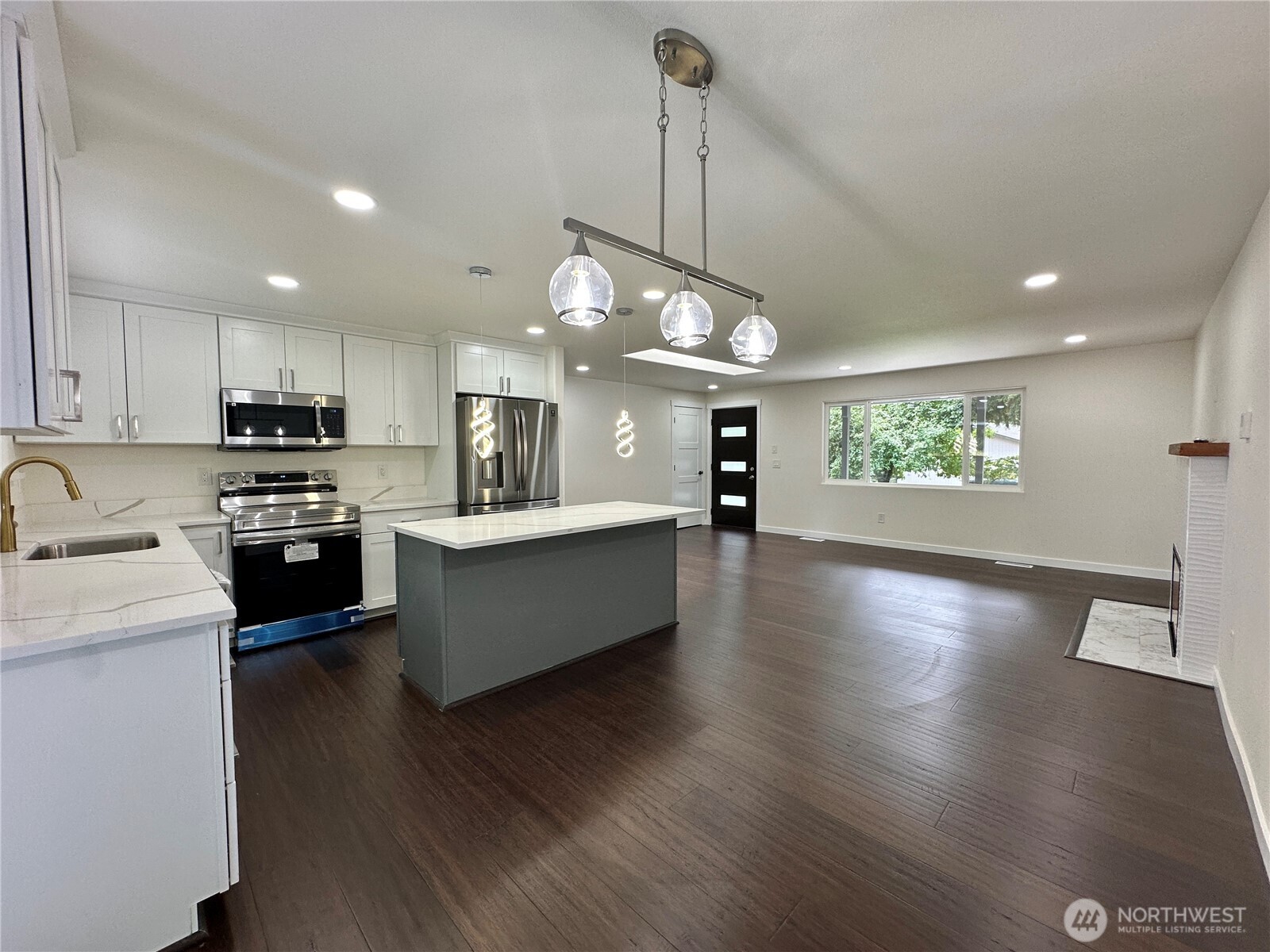 7044 Johnson Point Road Northeast Olympia, WA 98516 - Photo 4 of 36 a large kitchen with stainless steel appliances a large counter top a stove a sink dishwasher a kitchen island with wooden floor and cabinets