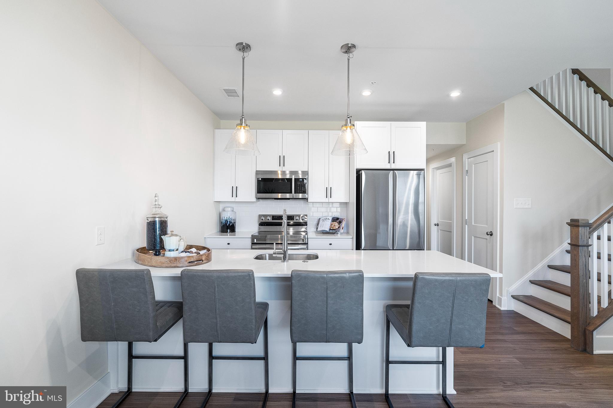 7 Mainland Road, Unit 102 Harleysville, PA 19438 - Photo 19 of 30 a kitchen with stainless steel appliances kitchen island granite countertop a table chairs and a refrigerator