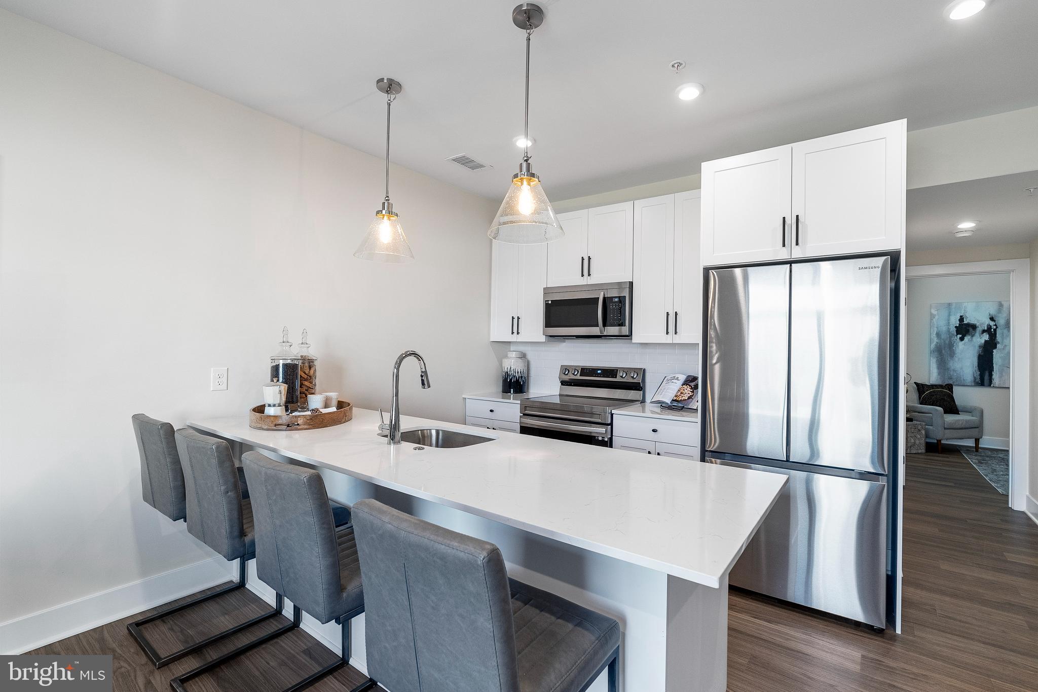 7 Mainland Road, Unit 102 Harleysville, PA 19438 - Photo 23 of 30 a kitchen with stainless steel appliances a table chairs refrigerator and microwave