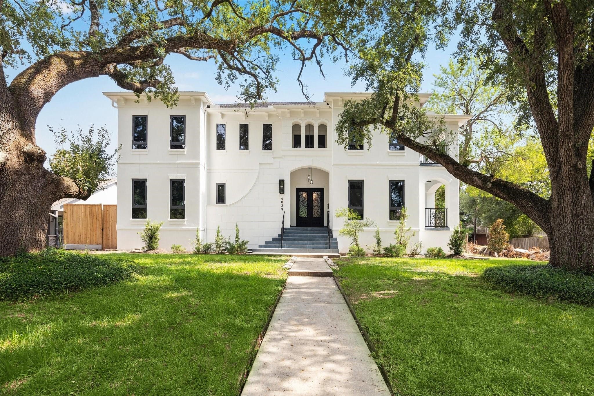 a view of a white house with a big yard and large trees