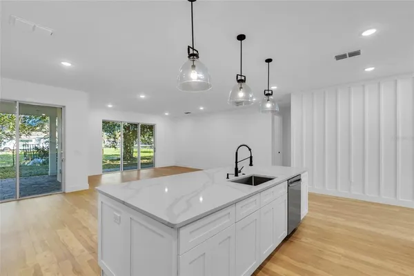 a kitchen with a sink chandelier and wooden floor