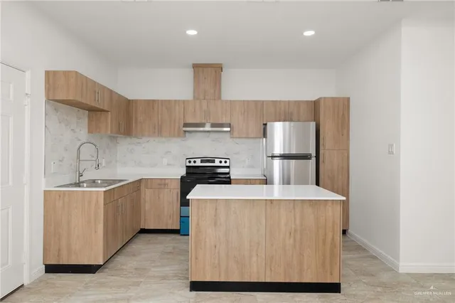 a kitchen with stainless steel appliances a sink stove refrigerator and cabinets