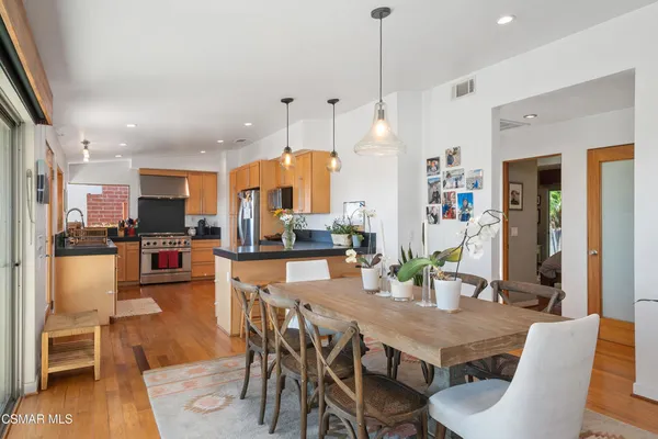 a view of a dining room and livingroom with furniture wooden floor a rug a fireplace and a chandelier
