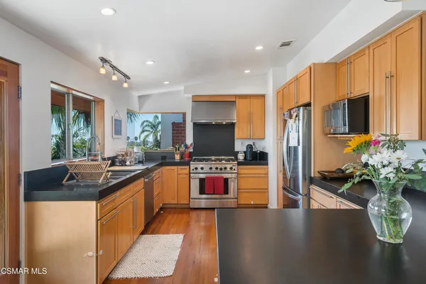 a kitchen with stainless steel appliances kitchen island granite countertop a stove refrigerator and a sink