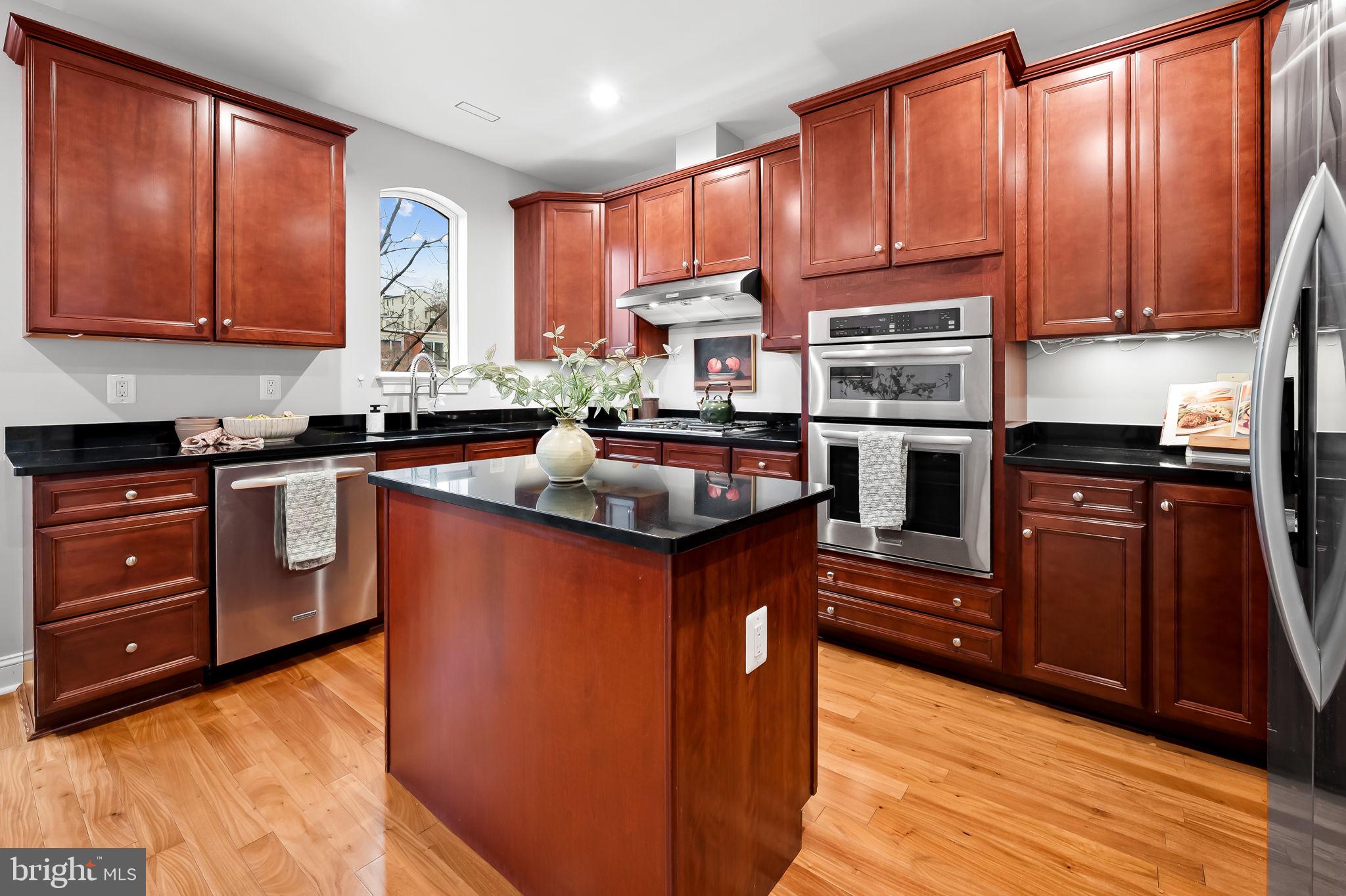 1024 Pier Pointe Landing, Unit 107 Baltimore, MD 21230 - Photo 4 of 51 a kitchen with stainless steel appliances granite countertop wooden cabinets a stove top oven a sink and dishwasher with wooden floor