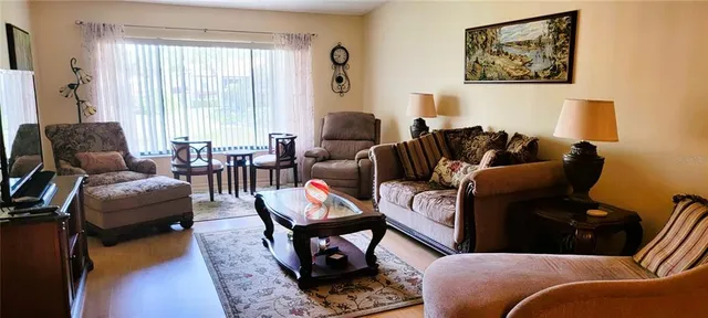 a living room with furniture a wooden floor and a large window