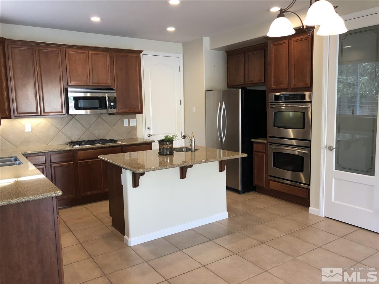 10112 Gold Mine Drive Reno, NV 89521 - Photo 3 of 22 a kitchen with kitchen island granite countertop a stove sink and refrigerator