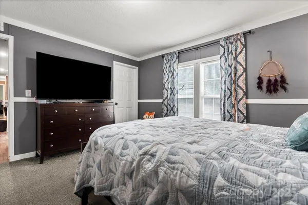 a bedroom with a bed and a flat tv screen on wall