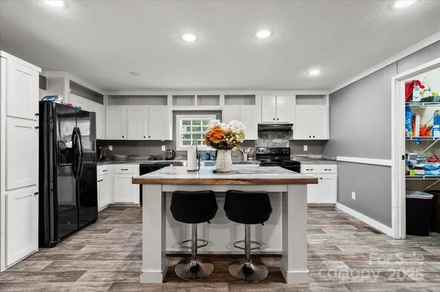 a kitchen with stainless steel appliances a dining table chairs stove refrigerator and cabinets