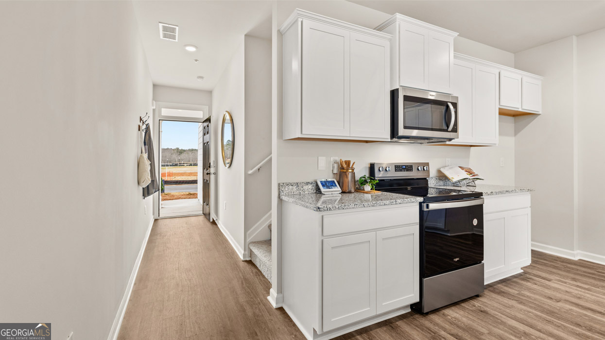 241 Sound Circle Stockbridge, GA 30281 - Photo 19 of 64 a kitchen with stainless steel appliances granite countertop white cabinets a sink a stove a microwave and wooden floors