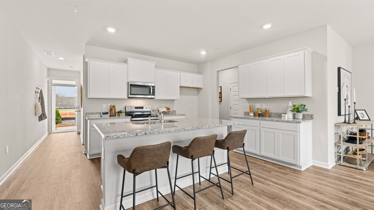 241 Sound Circle Stockbridge, GA 30281 - Photo 22 of 64 a kitchen with white cabinets and stainless steel appliances