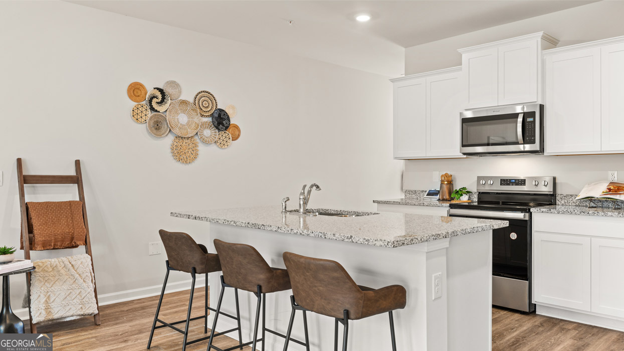241 Sound Circle Stockbridge, GA 30281 - Photo 23 of 64 a kitchen with kitchen island granite countertop a sink cabinets and stainless steel appliances