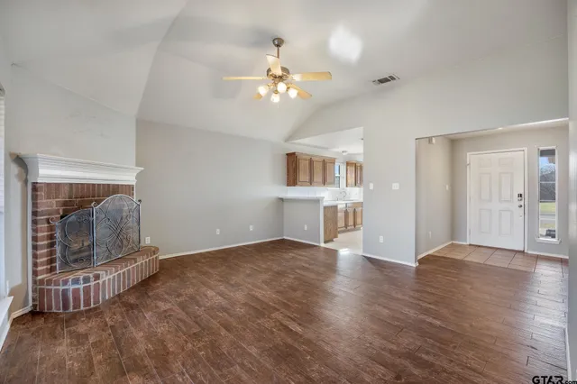 a view of an empty room with wooden floor and a fireplace