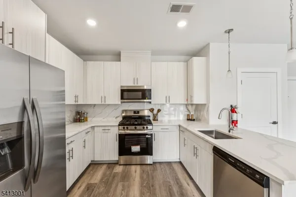 a kitchen with stainless steel appliances a sink dishwasher a refrigerator and a oven with wooden floor