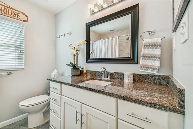 a bathroom with a granite countertop toilet sink and mirror