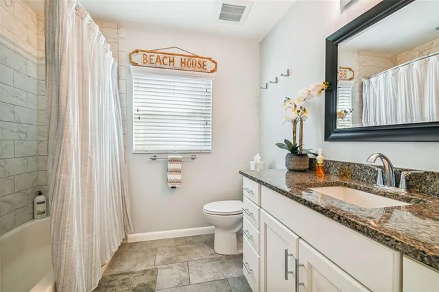 a bathroom with a granite countertop sink and a toilet
