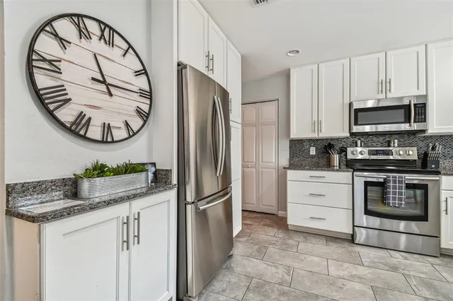 a kitchen with stainless steel appliances granite countertop a stove a refrigerator and a microwave