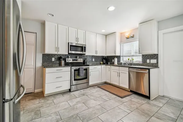 a kitchen with stainless steel appliances granite countertop a refrigerator sink and white cabinets