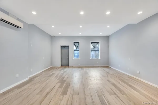 a view of an empty room with window and wooden floor