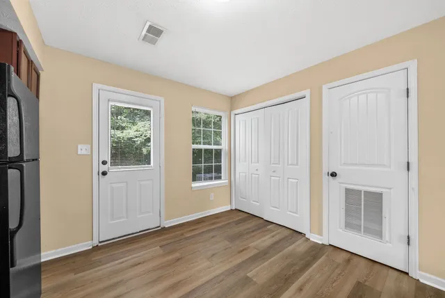 an empty room with wooden floor and windows