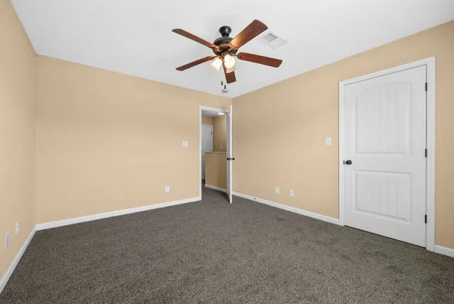 an empty room with closet and ceiling fan