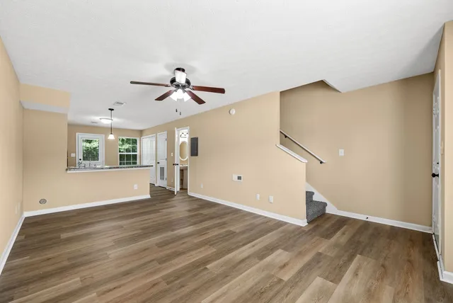 a view of an empty room with window and wooden floor